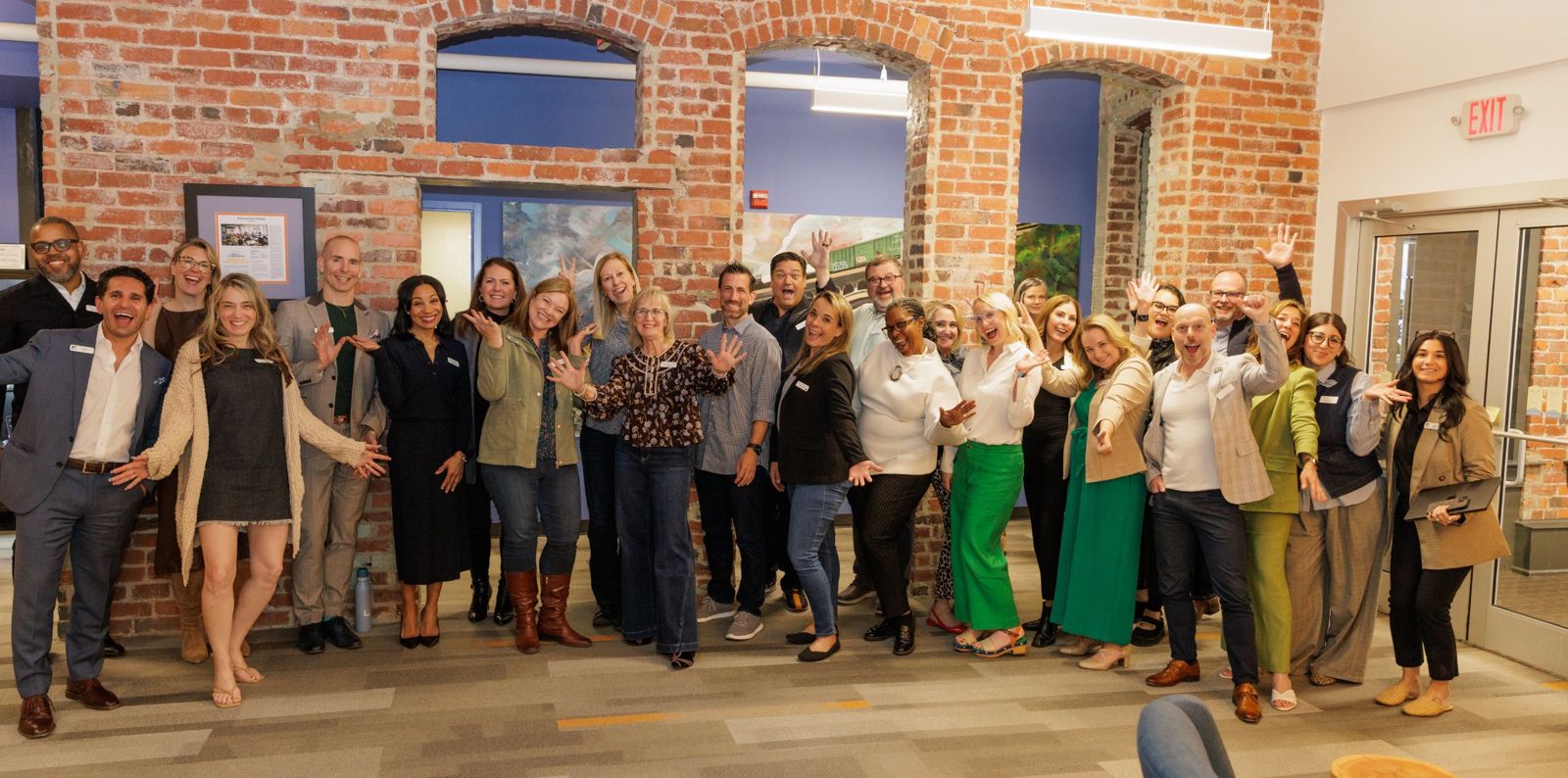 The Spring 2026 summit group celebrating together in front of a brick wall at Unboxed Headquarters